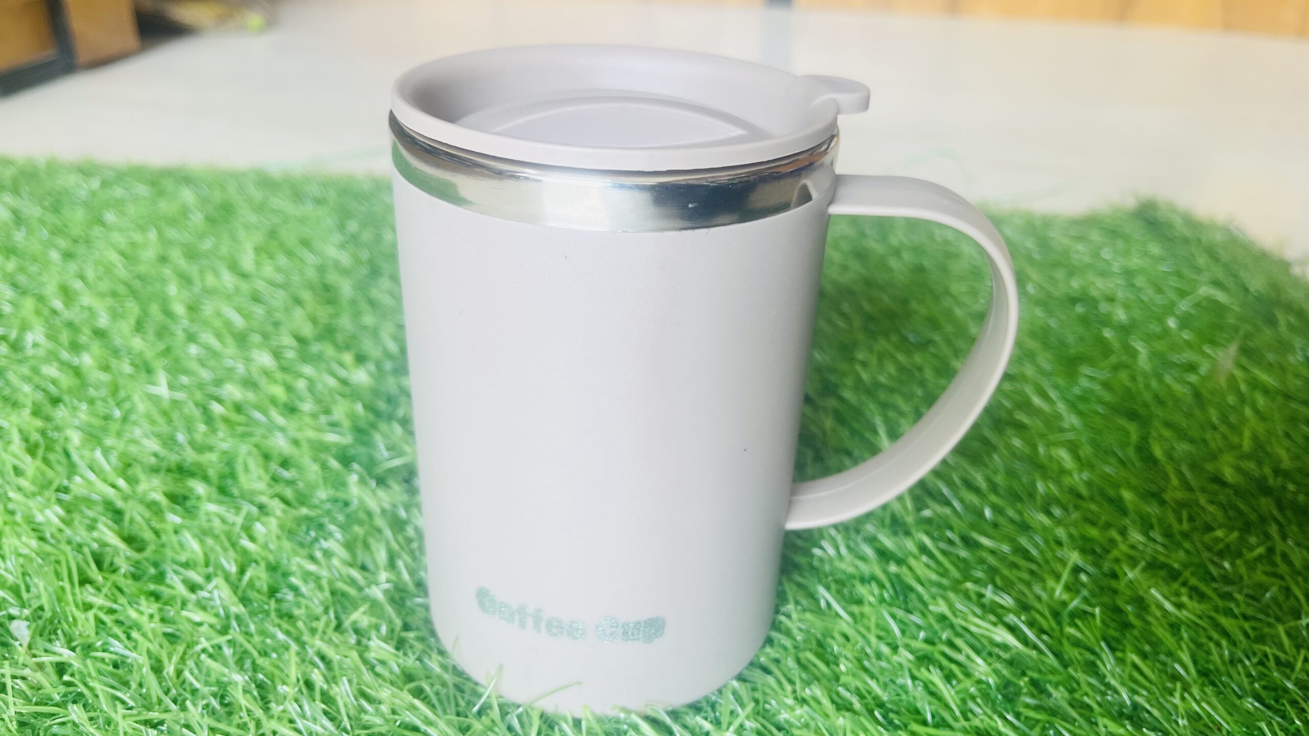 insulated stainless steel coffee mug with handle & sip lid (matte off white / beige, 380–450 ml) insulated coffee mug with handle on desk
